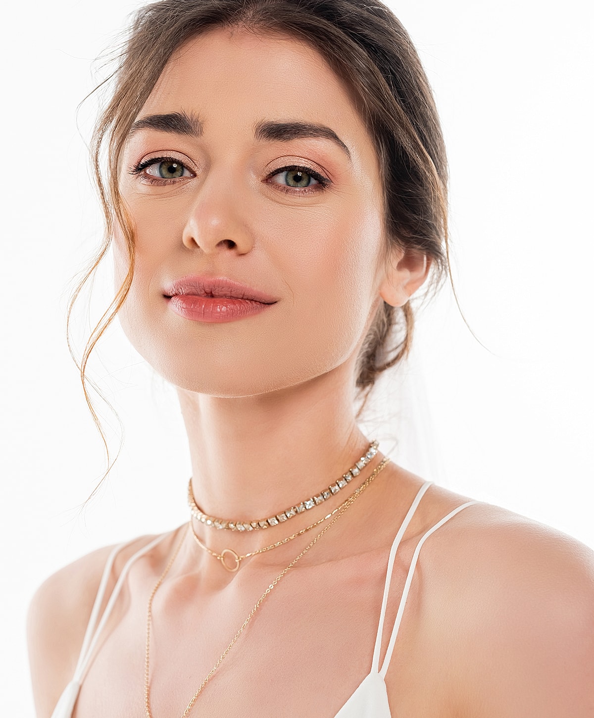 Woman with layered necklaces and soft makeup.